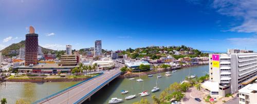 Oaks Townsville Gateway Suites في تاونزفيل: مدينة فيها جسر وقوارب في نهر