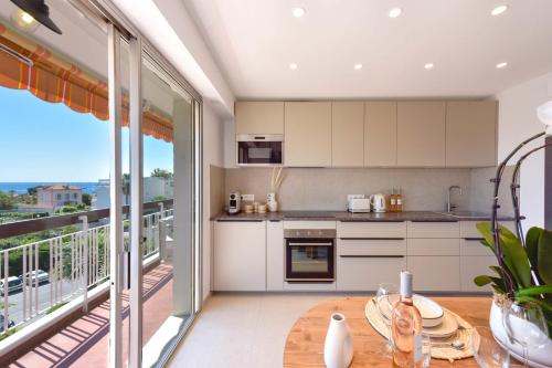Il comprend une cuisine avec des placards blancs et un balcon. dans l'établissement Luxury 1-Br apartment sea view parking, à Vallauris