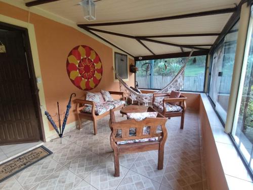 eine Veranda mit Stühlen, einem Tisch und Fenstern in der Unterkunft Chácara Toca da Zuca in Divino de São Lourenço