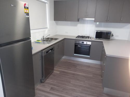 a kitchen with stainless steel appliances and white cabinets at French Corner Apartments in Dubbo