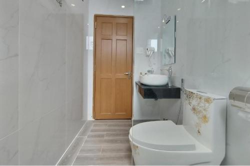 La salle de bains blanche est pourvue de toilettes et d'un lavabo. dans l'établissement HANZ Hoa Dang Hotel, à Đà Lạt