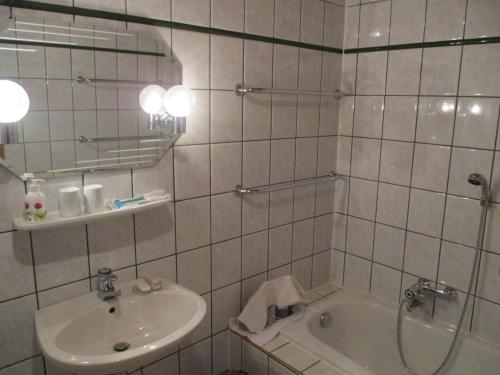 a white tiled bathroom with a sink and a tub at Haus 33 Top 1 in Krimml