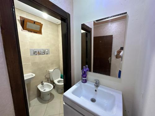 ein Badezimmer mit einem Waschbecken, einem WC und einem Spiegel in der Unterkunft Tourist complex City Center Oued Laou in Oued Laou