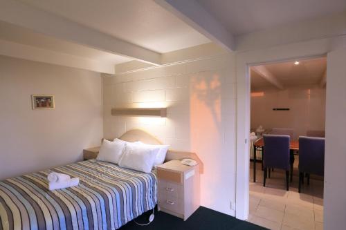 a hotel room with a bed and a dining room at Ocean Views Motel Lakes Entrance in Lakes Entrance