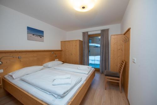 a bedroom with a large bed and a chair at Almhäuser Filzsteinalpe Almhaus 201 in Krimml