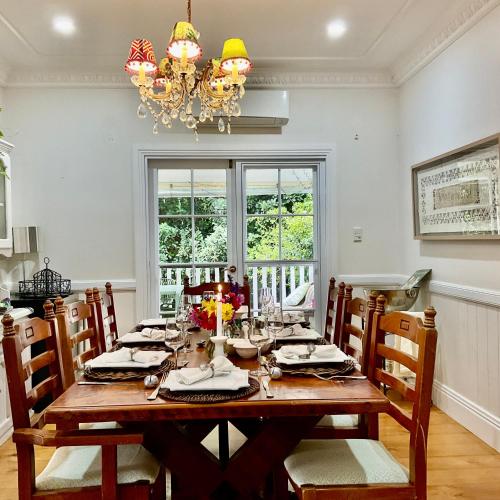 a dining room with a table with chairs and a chandelier at Middleton House Maleny in Witta