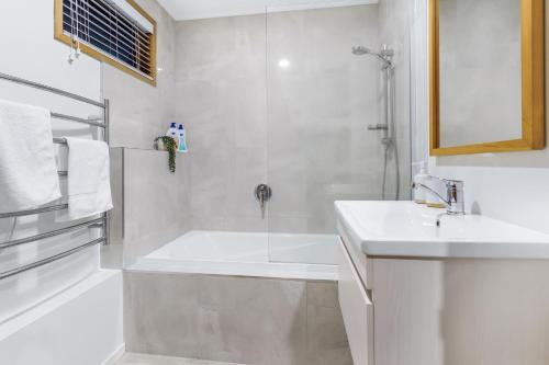 a white bathroom with a shower and a sink at Tree Top Retreat in Central City - By KOSH BNB in Hamilton