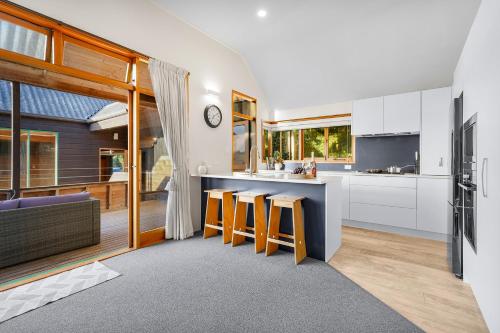 a kitchen with white cabinets and a bar with stools at Tree Top Retreat in Central City - By KOSH BNB in Hamilton