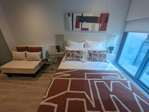 a bedroom with a bed and a couch in a room at Cosy City Studio Apartment in Melbourne