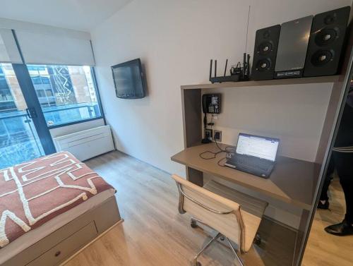 a room with a desk with a laptop and a bed at Cosy City Studio Apartment in Melbourne