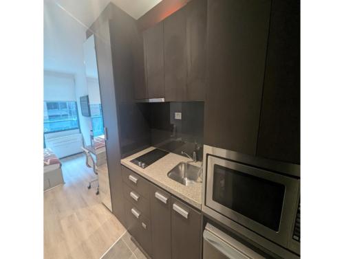 a kitchen with a sink and a microwave at Cosy City Studio Apartment in Melbourne