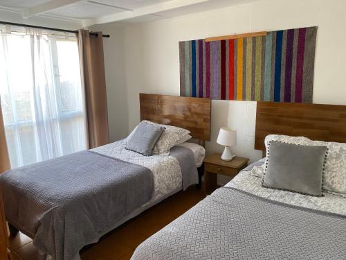 Habitación de hotel con 2 camas y ventana en ALOJAMIENTO AVENIDA DEL MAR CABAÑA LA SERENA, en La Serena