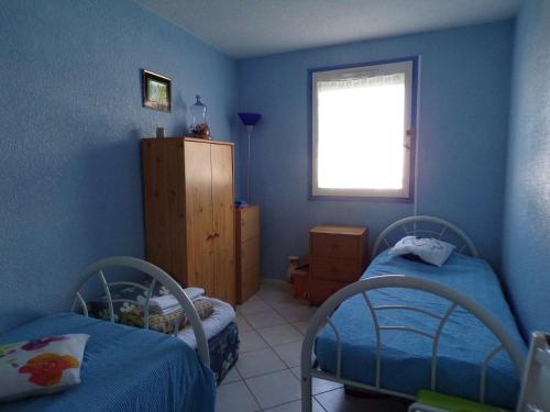 Cette chambre bleue comprend 2 lits et une fenêtre. dans l'établissement Appartement 3 pièces avec loggia, jardin, accès direct plage, garage - La Grande-Motte - FR-1-328-111, à La Grande Motte