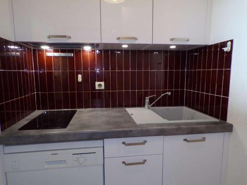 Il dispose d'une cuisine avec un évier et un mur en carrelage rouge. dans l'établissement Appartement 2P en bord de mer avec parking, La Grande-Motte - FR-1-328-202, à La Grande Motte