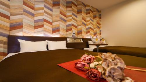 a bedroom with a bed with flowers on a table at Hotel New Gaea Yanagawa in Yanagawa