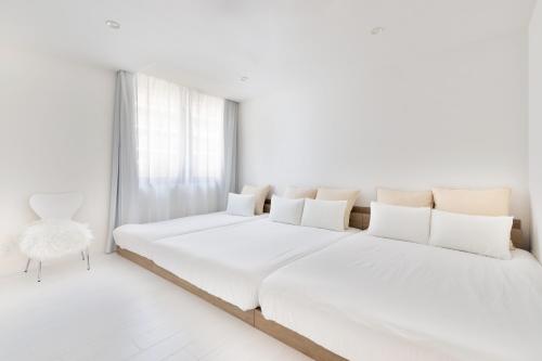 a white bedroom with two beds and a chair at City Hotel Namba Prime in Osaka