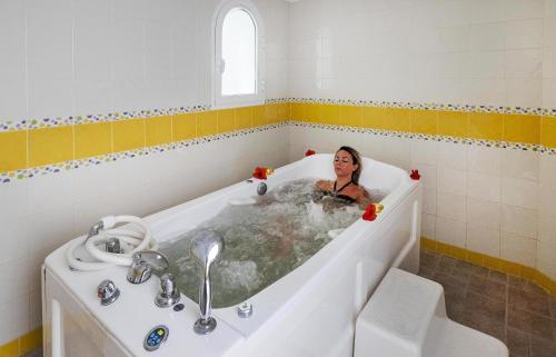 a woman sitting in a bath tub in a bathroom at Houda Yasmine Marina & SPA in Hammamet