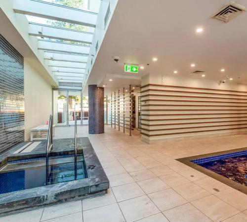 a lobby with a swimming pool in a building at Glenelg Oasis, Pool, Gym, Spa & Sauna, Free Parking, City Views in Glenelg