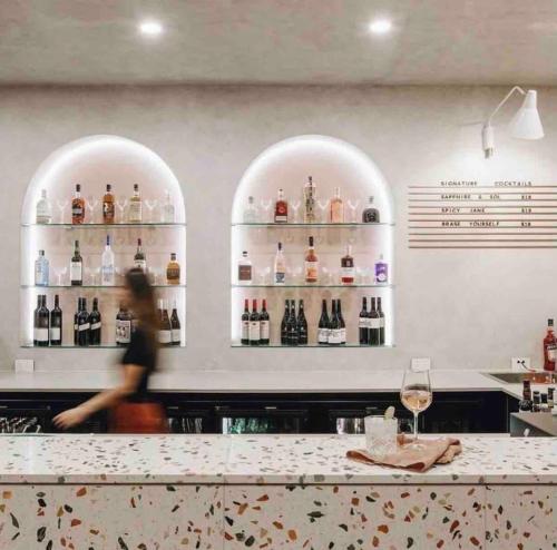 a person walking past a bar with shelves of wine bottles at Glenelg Oasis, Pool, Gym, Spa & Sauna, Free Parking, City Views in Glenelg