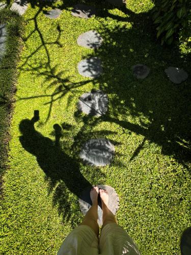 a person sitting on the grass with their feet on the grass at Nirwa Ubud Karma in Ubud