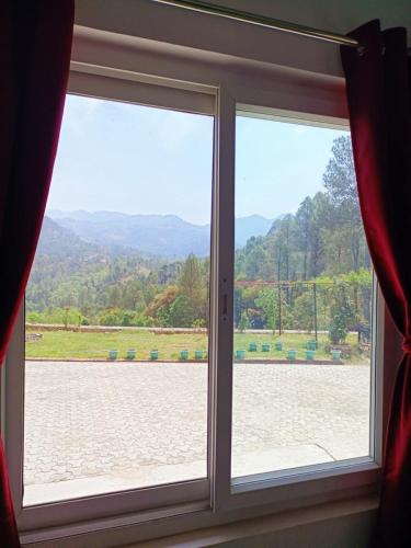 a window with a view of a field at Trails of Bheta in Kausani