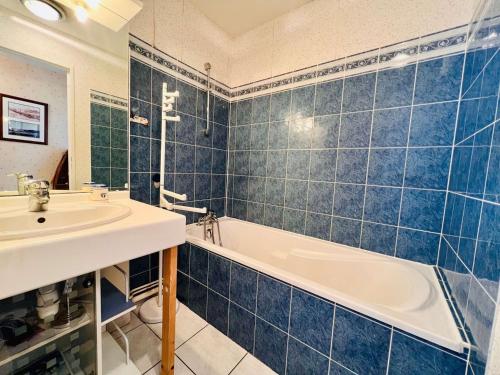 La salle de bains est pourvue de carrelage bleu, d'une baignoire et d'un lavabo. dans l'établissement Appartement T3 70m² à Quiberon avec parking et WiFi, proche plage - FR-1-478-293, à Quiberon