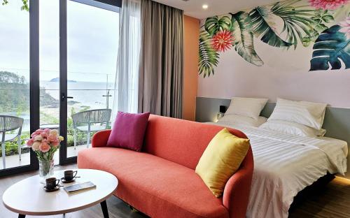 een slaapkamer met een bed, een bank en een tafel bij Flamingo Hải Tiến in Nam Khê