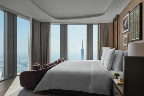a large white bed in a room with large windows at Rosewood Guangzhou, enjoy free shuttle bus service between the hotel and the Canton Fair Complex during the Canton Fair in Guangzhou