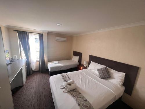 ein Hotelzimmer mit 2 Betten und einem Fenster in der Unterkunft Prince of Wales Hotel, Bunbury in Bunbury