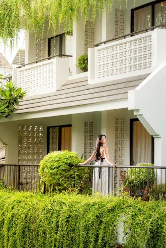 a woman standing on a balcony in front of a building at The Saga Hotel Hoi An in Hoi An