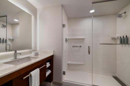 uma casa de banho branca com um chuveiro e um lavatório. em Residence Inn Panama City Beach Pier Park em Panama City Beach