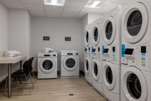 a laundry room with three washing machines and a table at Residence Inn Panama City Beach Pier Park in Panama City Beach