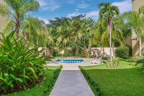 a garden with a swimming pool and palm trees at Fiesta Inn Colima in Colima