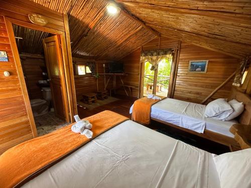 a bedroom with two beds in a wooden cabin at El Pajas in Puerto Velasco Ibarra