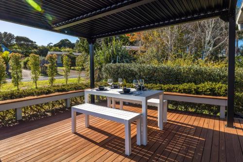 a white table and a bench on a wooden deck at Sweet Hartley - Onetangi Holiday Home in Onetangi