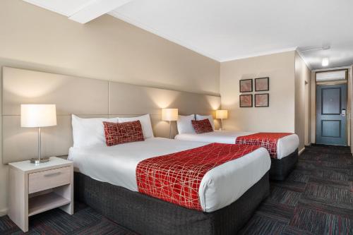 a hotel room with two beds with red sheets at Quality Hotel Parklake Shepparton in Shepparton