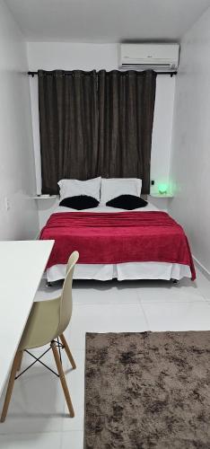 ein Schlafzimmer mit einem Bett mit einer roten Decke und einem Fenster in der Unterkunft Suíte Singular in Boa Vista