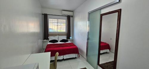 ein kleines Schlafzimmer mit einem Bett und einem Spiegel in der Unterkunft Suíte Singular in Boa Vista