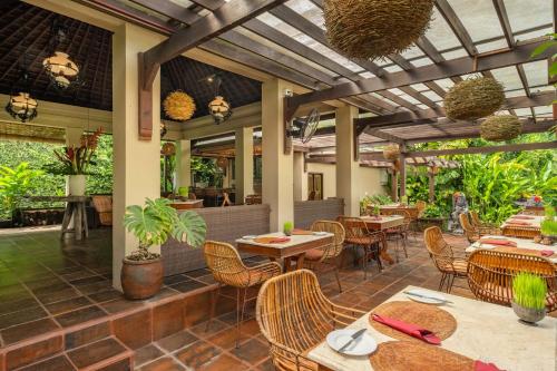 eine Außenterrasse mit Tischen und Stühlen sowie ein Restaurant in der Unterkunft Villa Semana Resort & Spa in Ubud