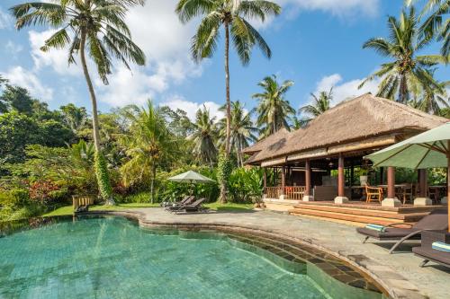 a resort swimming pool with palm trees in the background at Villa Semana Resort & Spa in Ubud