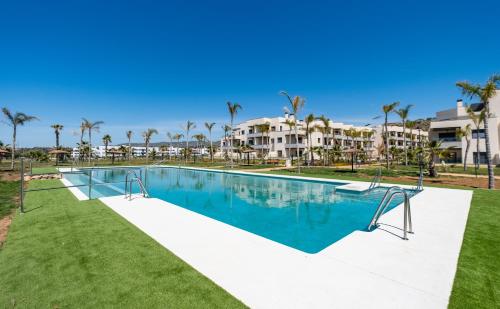 una piscina en un complejo con palmeras en El amanecer, Apartamento 1 linea de playa en Vélez-Málaga
