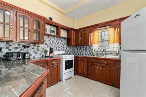 a kitchen with wooden cabinets and a white stove top oven at Kaibus Place K3 2/bedroom in Morne Rouge