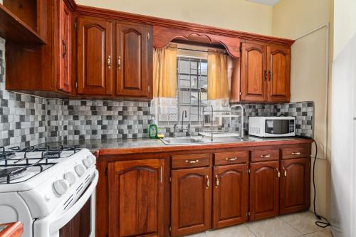 a kitchen with wooden cabinets and a white stove top oven at Kaibus Place K3 2/bedroom in Morne Rouge