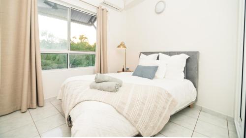 a white bedroom with a large bed with a window at Tropical Bliss in Woolner in Stuart Park