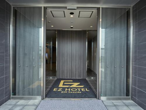 une entrée à un hôtel avec un panneau sur la porte dans l'établissement EZ HOTEL 関西空港 Seaside, à Izumi-Sano