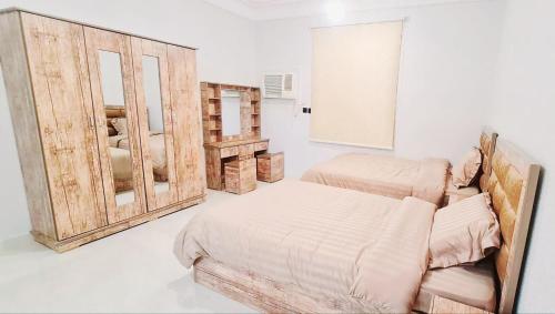 sypialnia z 2 łóżkami i drewnianymi drzwiami w obiekcie السلطان شقق سكنية مستقلة Private independent w Medynie