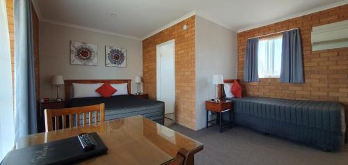 een hotelkamer met 2 bedden, een tafel en een bureau bij Centrepoint Motel Deniliquin in Deniliquin