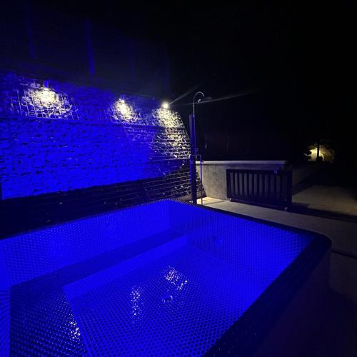 a dark room with a hot tub with blue lights at ケーブキャビン シービュー BBQ ピザ サウナ ホットタブ - Cave Cabin Chiba Seaview BBQ Pizza Sauna Hot-tub in Kobama