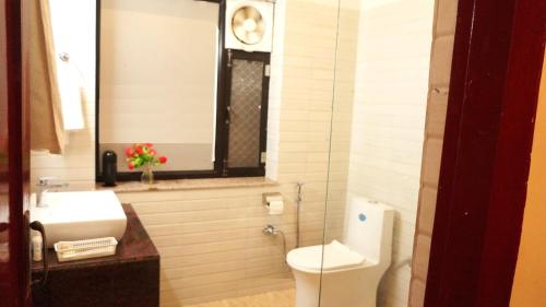 a bathroom with a toilet and a sink and a window at Wow Relish in Alwar