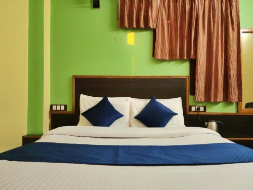 1 cama con almohadas azules y blancas y pared verde en Hotel Tirupati Regency Anandam en Shimla
